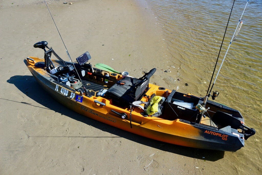 A fishing kayak on the shores of a river.