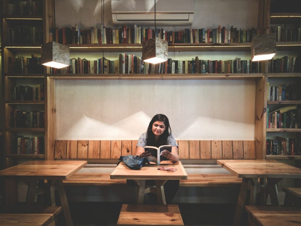 Student reading a book at a table