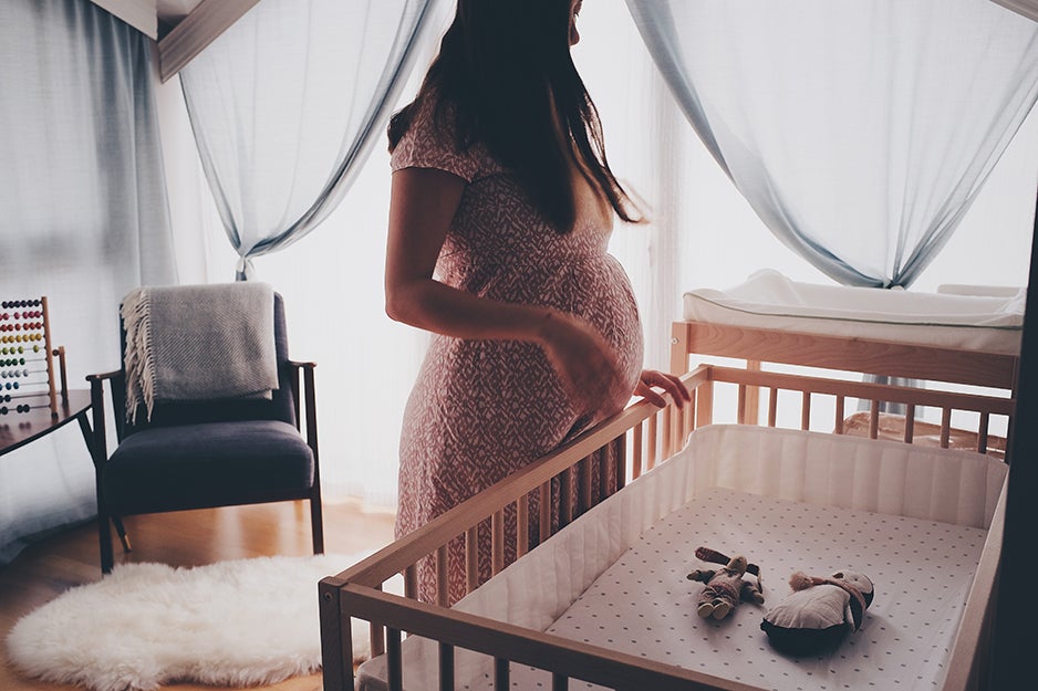 pregnant woman in front of a crib