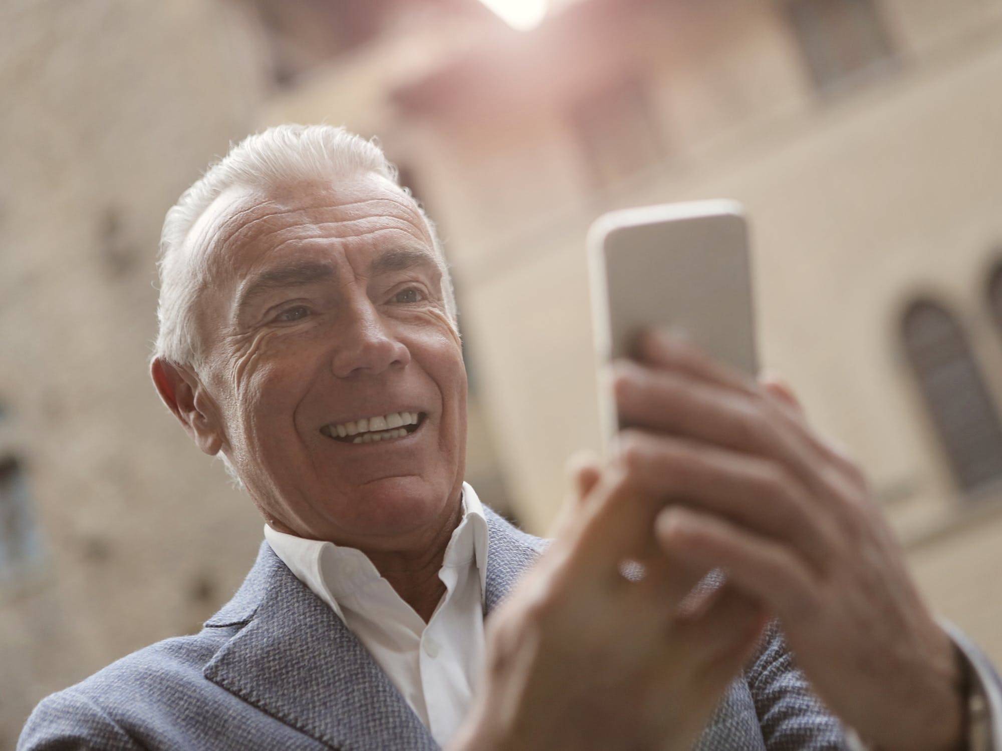 An elderly man on a video call in a public space.