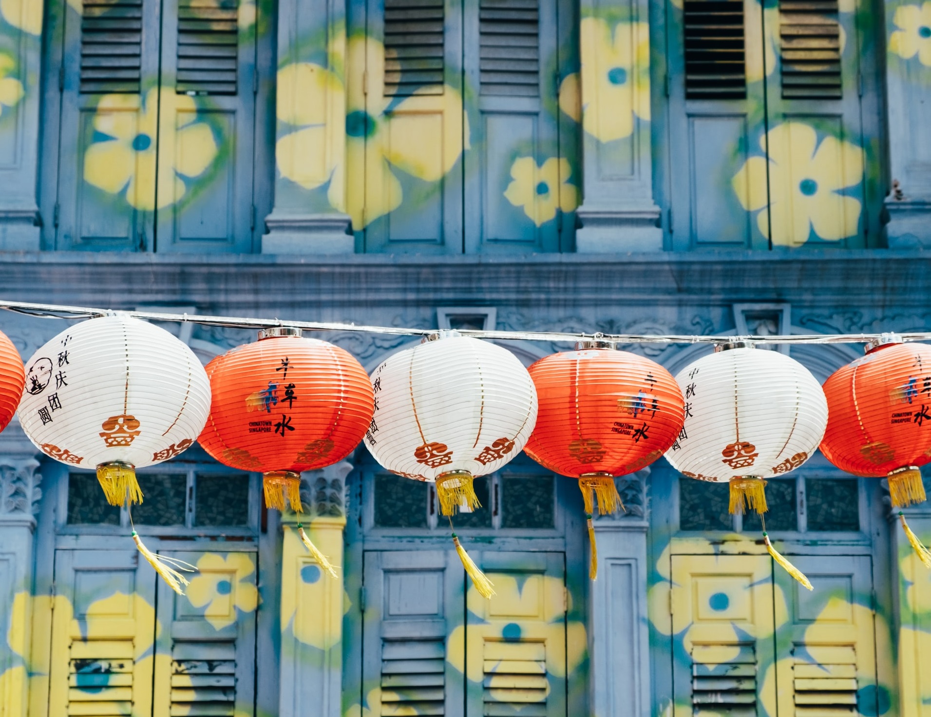 Chinese paper lanterns in front of a blue and yellow floral mural