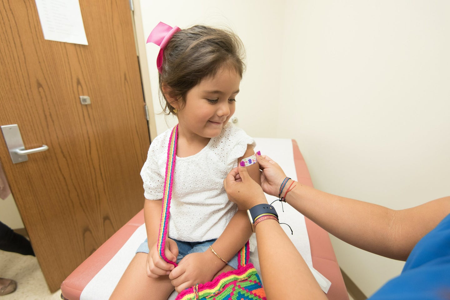 a girl getting a bandaid after receiving a vaccine.