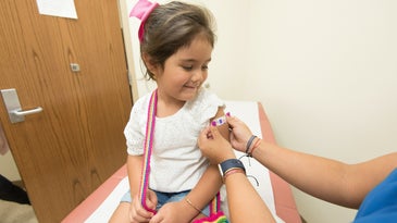 a girl getting a bandaid after receiving a vaccine.