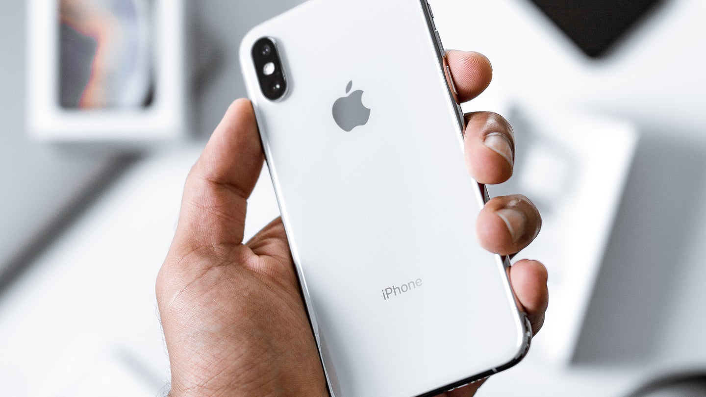 a person holding a white Apple iPhone in their hand