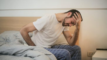 Man with headache on bed.