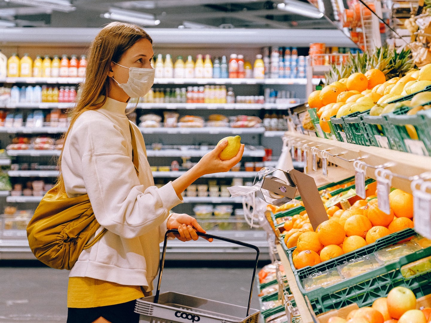 woman wearing a mask in a grocery store holding produce