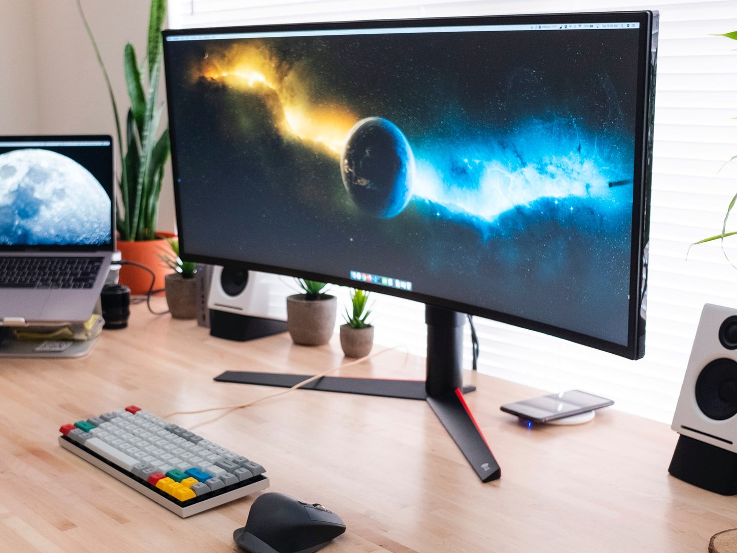 An ultrawide monitor on a wooden desk in front of a window.