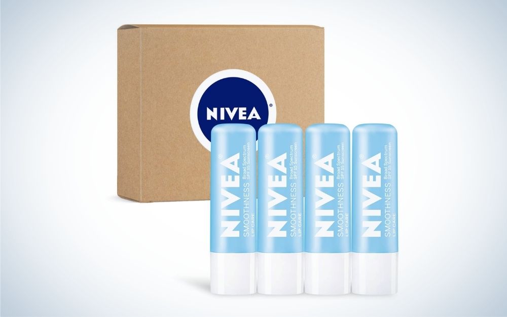 Four Nivea Lip Balm in line with each other in light blue color and a brown wooden box under them.