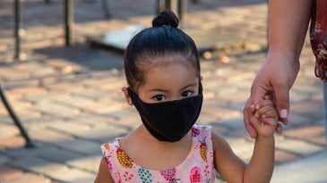A toddler with a black mask on