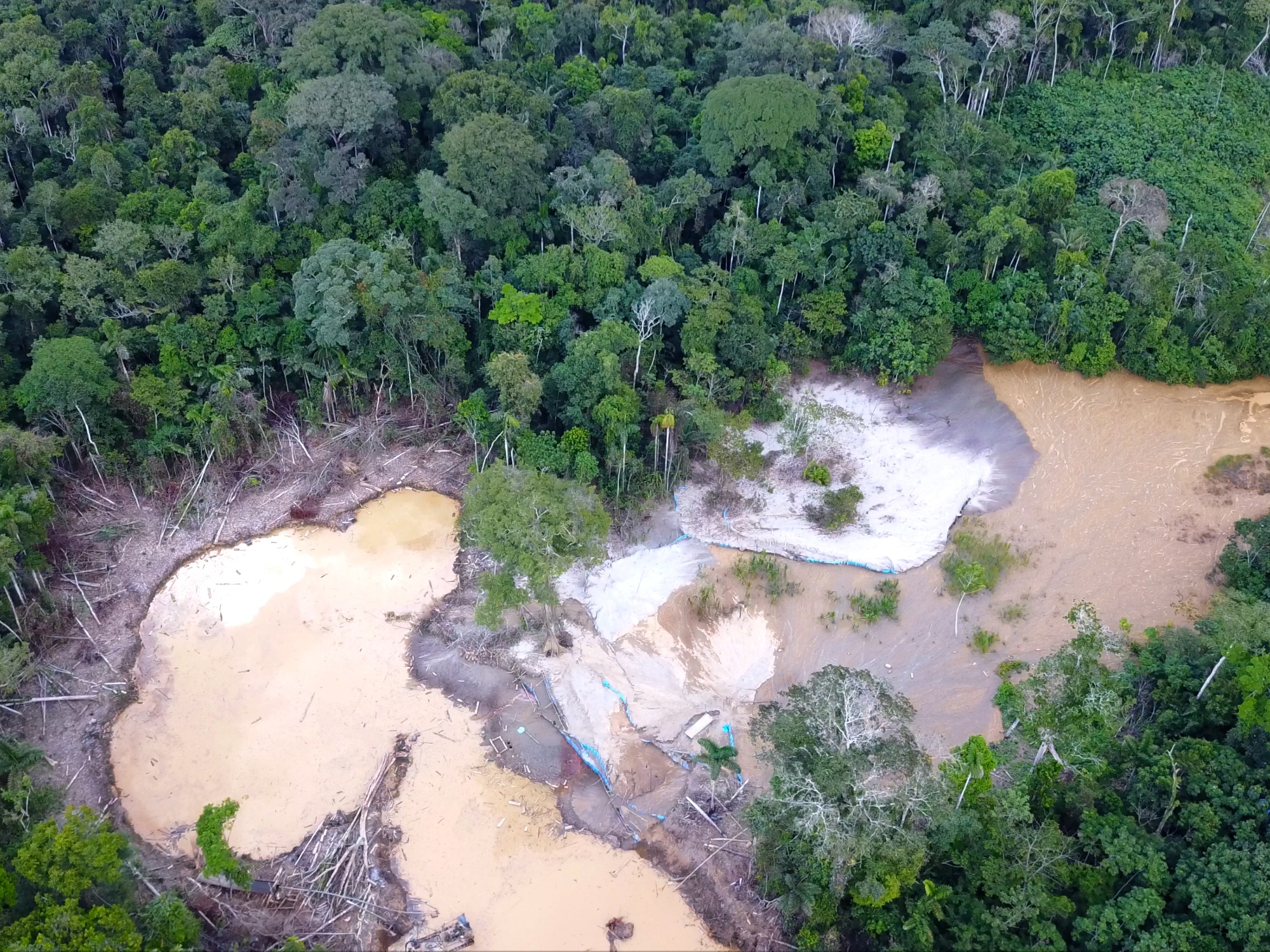 A drone-photograph shows an illegal mine in the middle of the Amazon rainforest. The image shows two artisanal pools, where the miners separate gold from rocks using mercury.