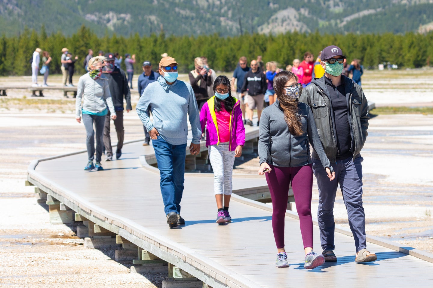 people walking on path at geysers in yellowstone