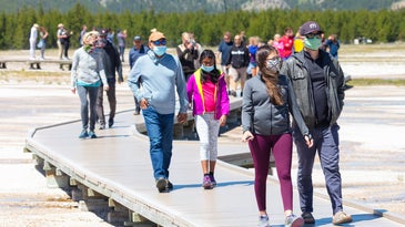 people walking on path at geysers in yellowstone