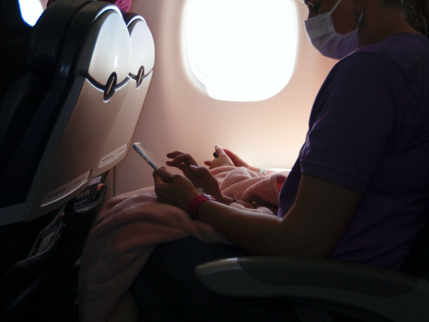 someone in an airplane seat with a mask on