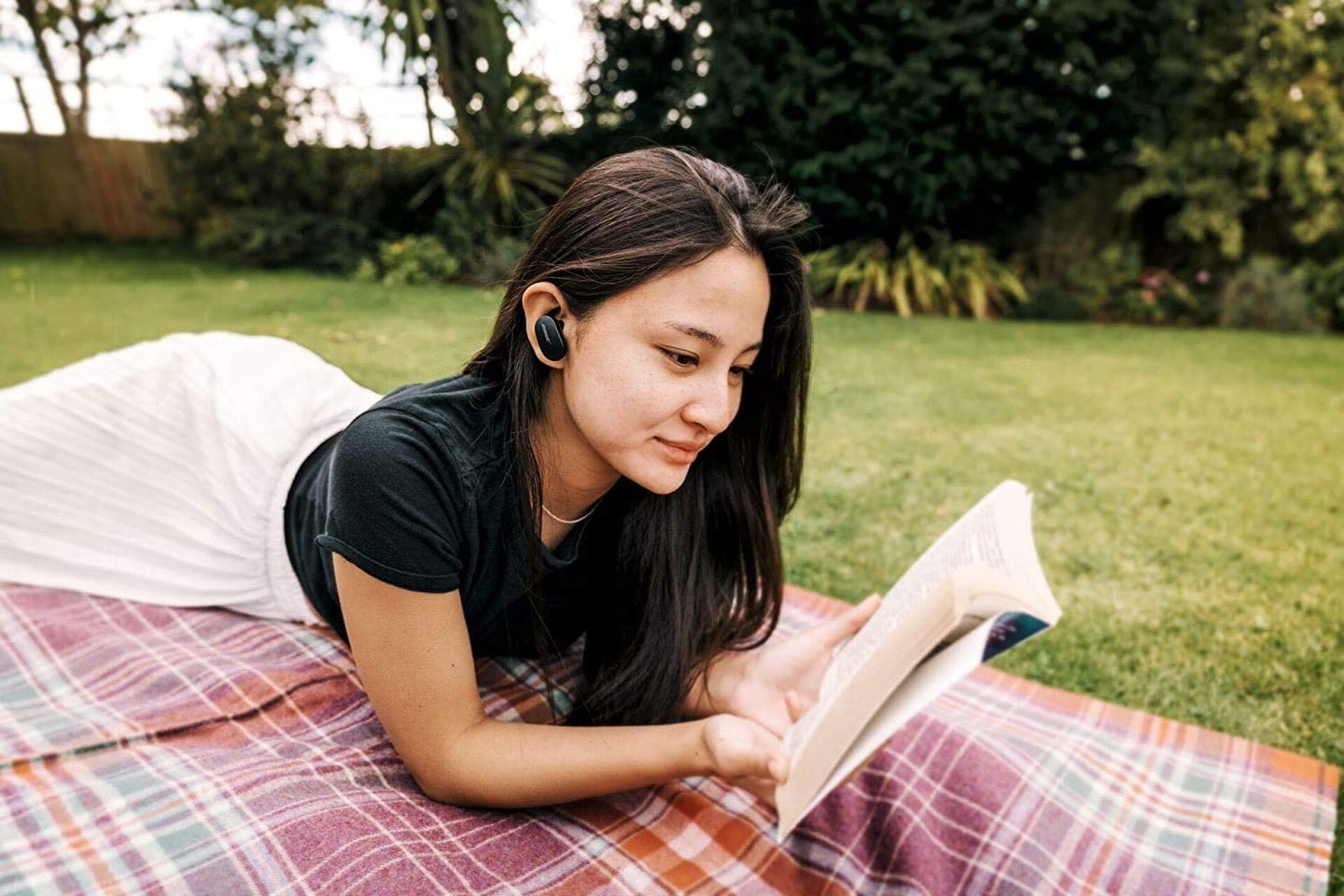 woman with earbuds reading a book
