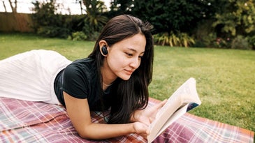 woman with earbuds reading a book