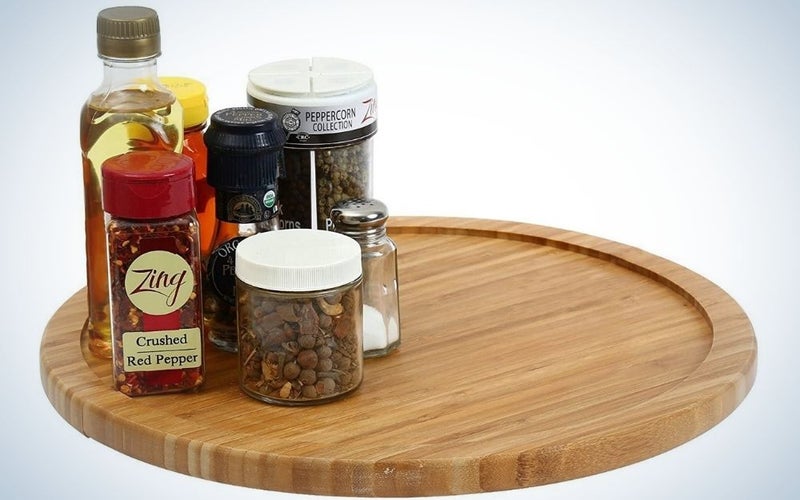 A round turntable cabinet and wooden color as well as a series of jars with spices and different flavors.