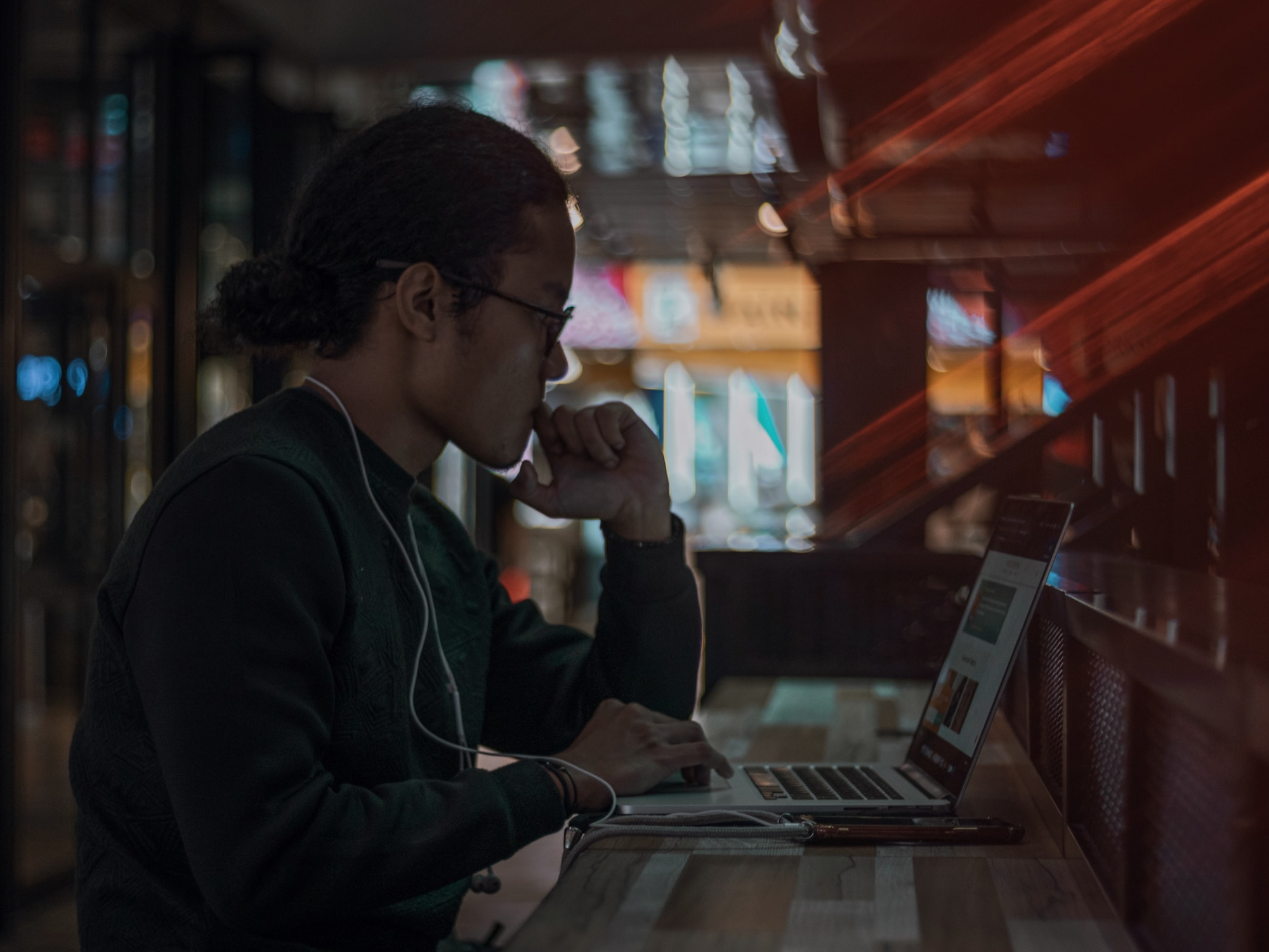 A person sitting in a cafe at night, using a laptop.