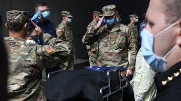 National guard members salute a veteran who died from COVID-19 at the Javits Center field hospital in New York City