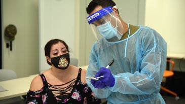 National guard members assist with point-of-care testing in Tempe, Arizona wearing face shields and plastic suits