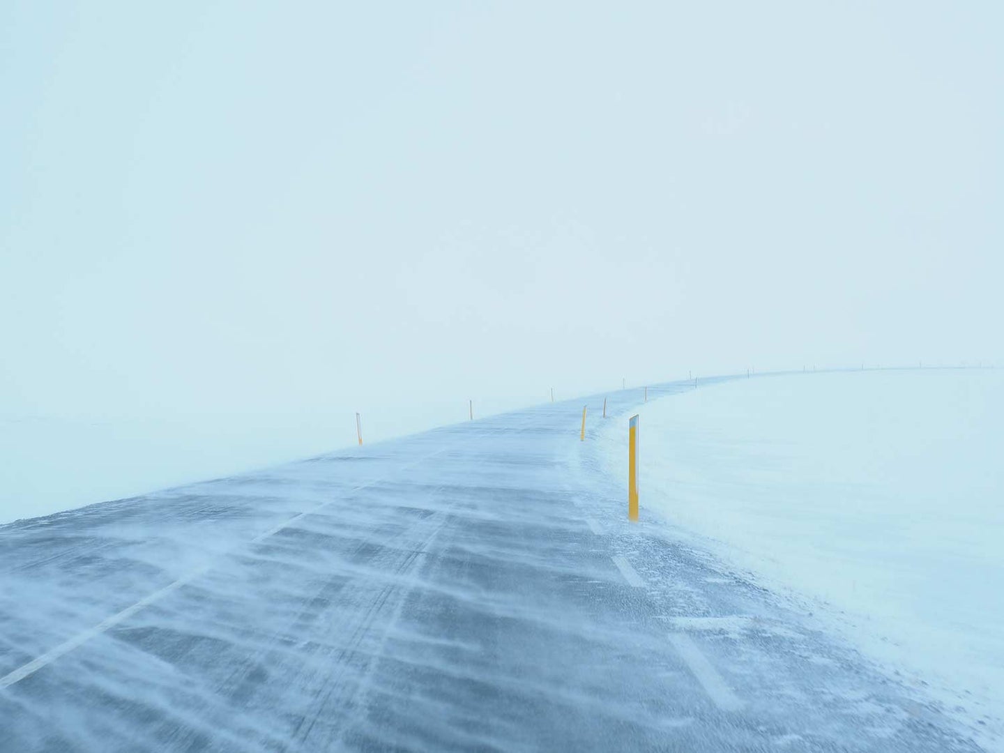 An image of a road covered in snow during a blizzard.