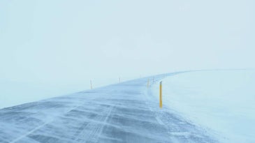 An image of a road covered in snow during a blizzard.