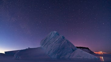 The starry Arctic sky over an iceberg in Greenland