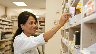 A pharmacist picking a medication off a shelf