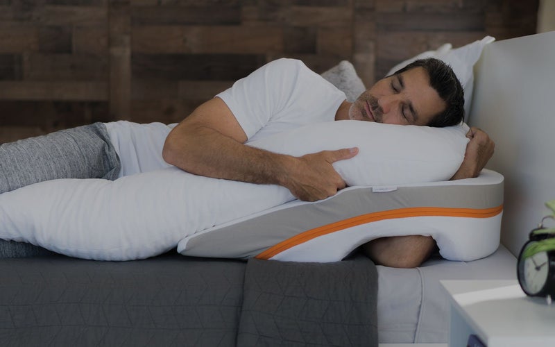 Un hombre duerme sobre una almohada de cuña.