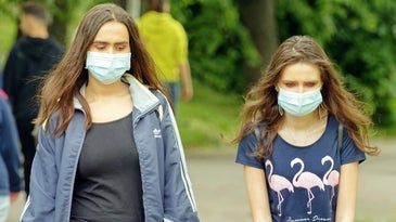 two women wearing masks outside