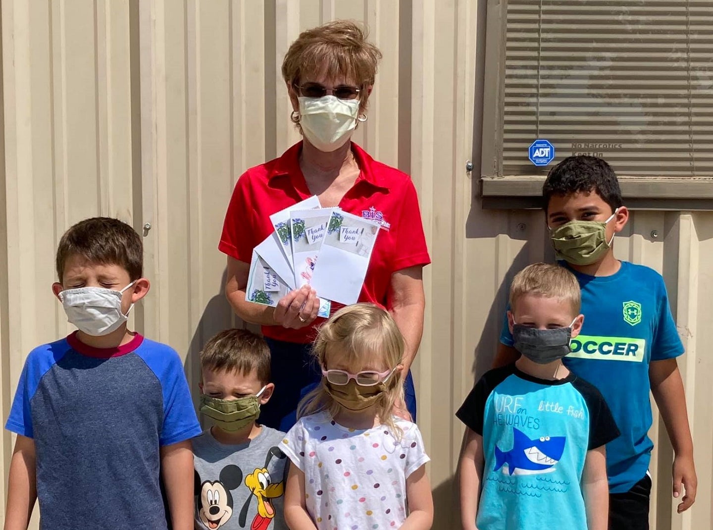 A nurse practitioner and kids wearing masks in front of a rural Texas COVID-19 clinic