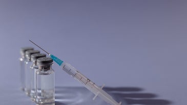 a syringe next to vials of vaccines