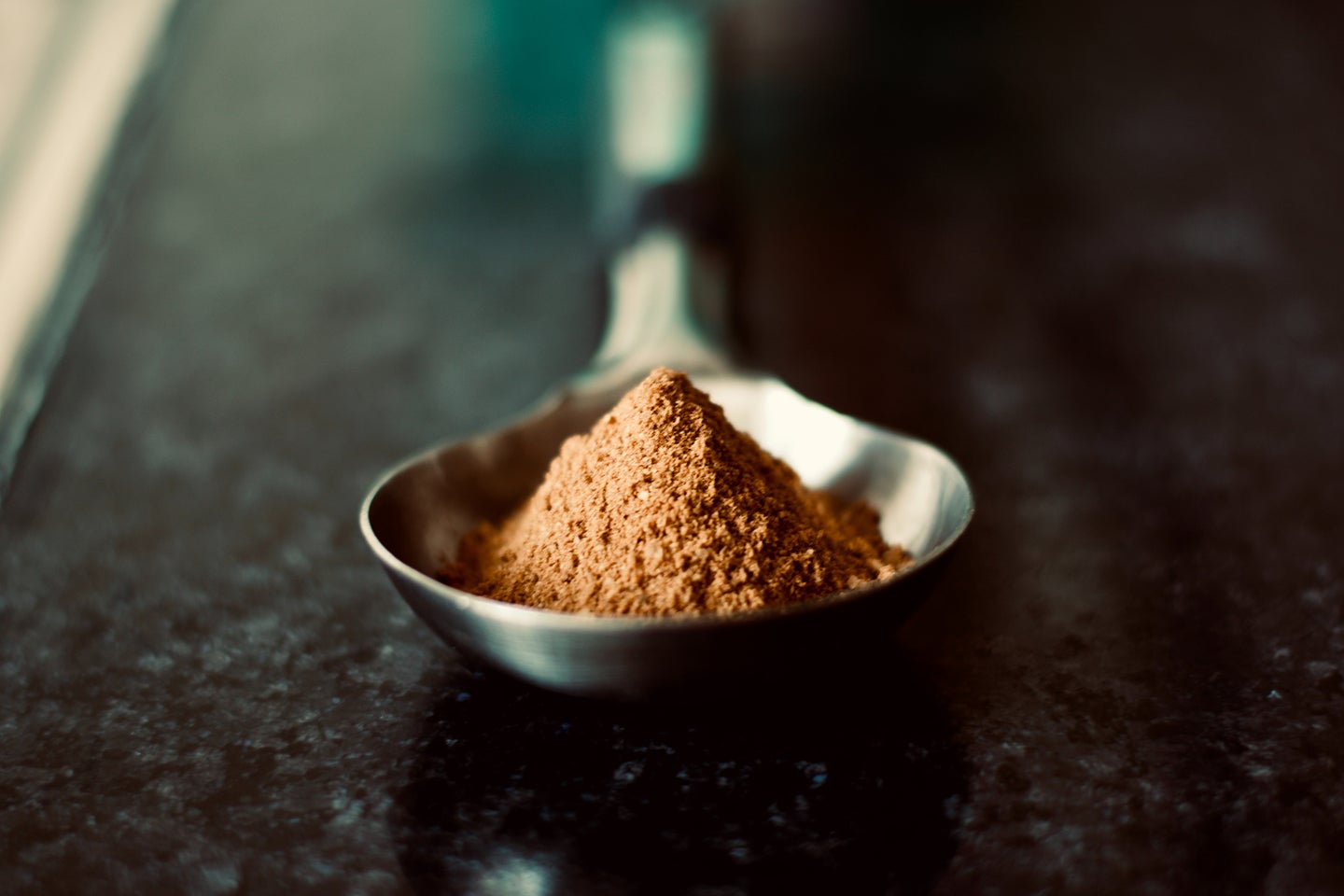 brown protein powder in a silver spoon