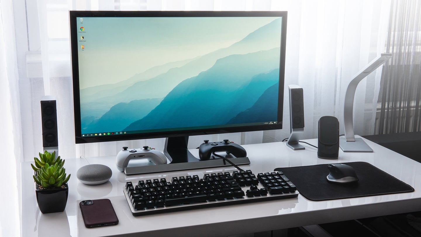 computer on a desk with keyboard, mouse, iphone, gaming controllers, and the best computer speakers