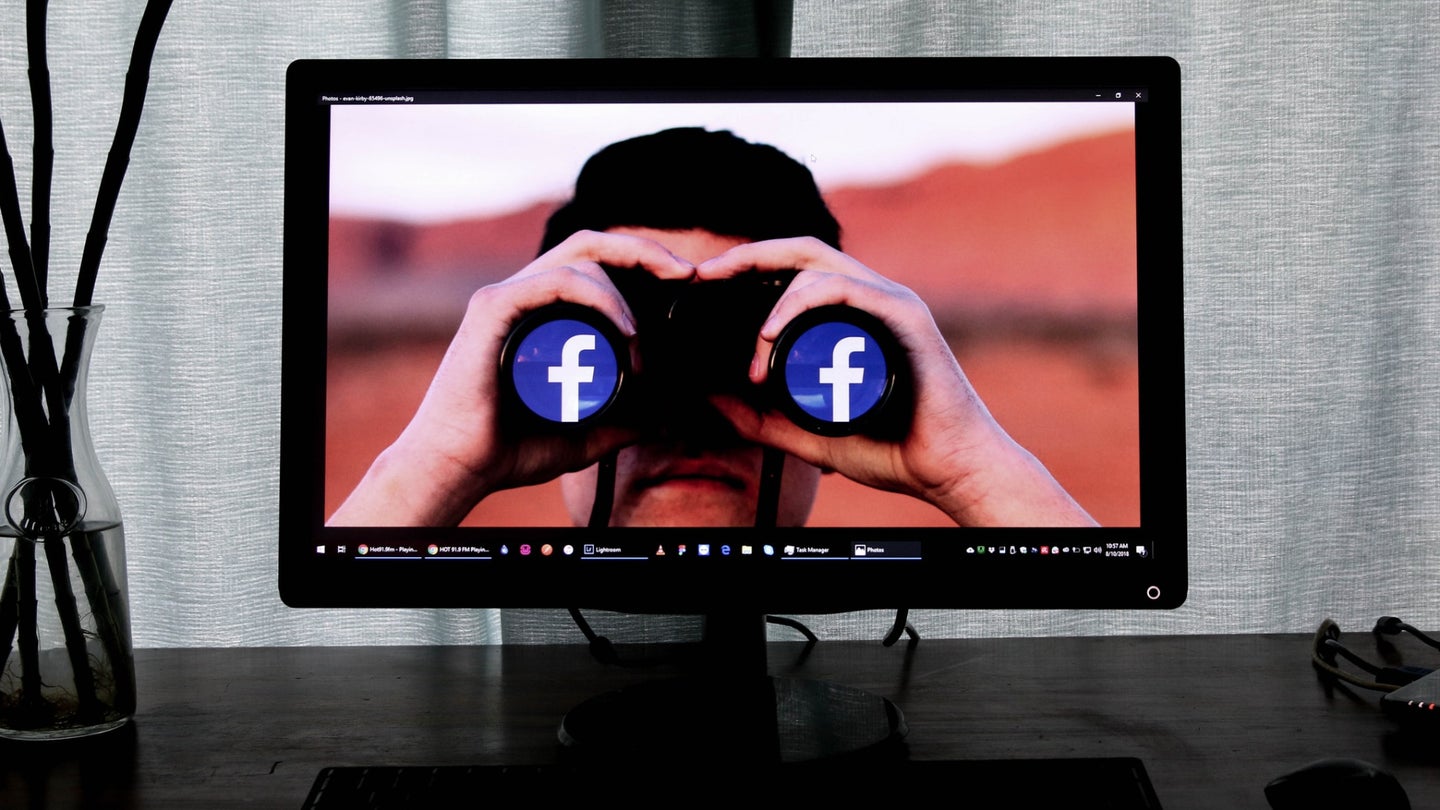 A man with bionoculars featuring the Facebook icon looking out from a desktop computer screen.