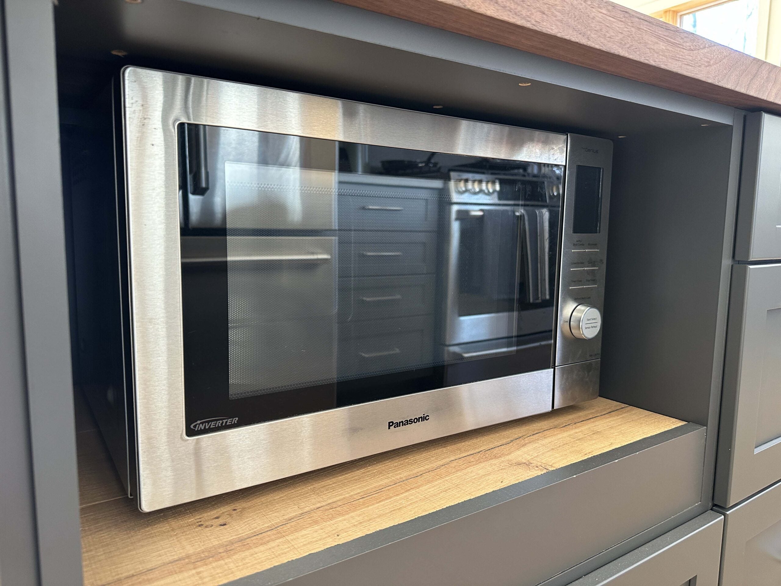 Panasonic Home Chef 4-in-1 Microwave sitting underneath a kitchen island on a wooden shelf