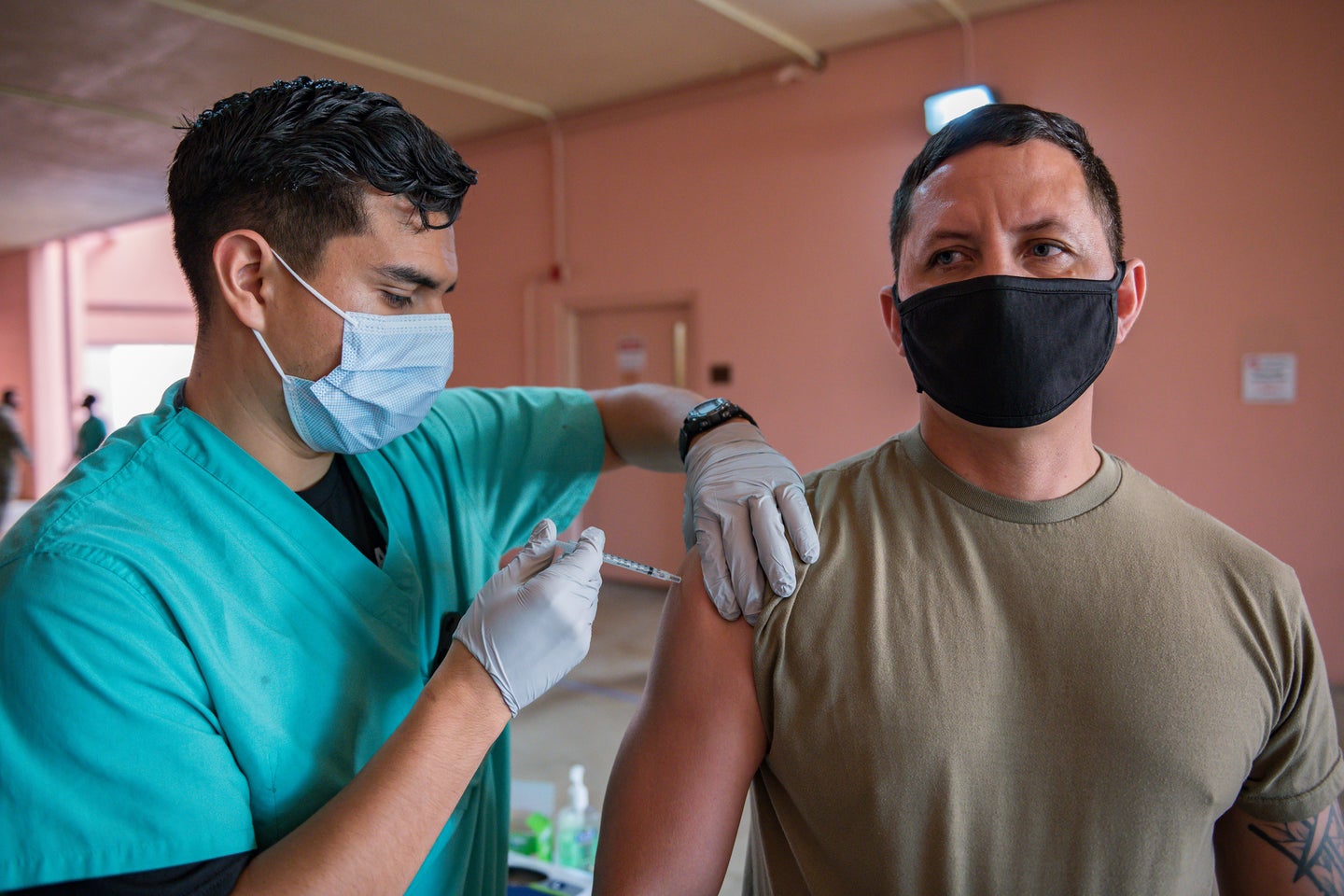 Hawaiian National Guard member gets a COVID-19 vaccine from a health care worker in scrubs