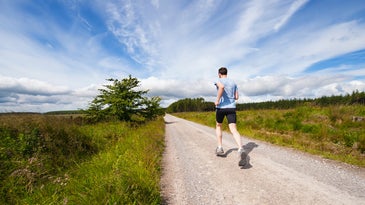 A guy running next to fields in a pair of the best running shoes for men