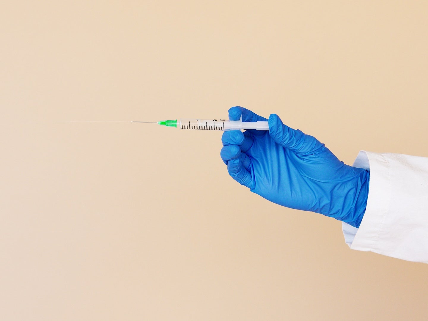 vaccine syringe held out by a gloved hand