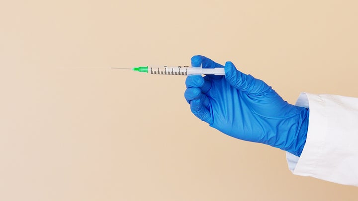 vaccine syringe held out by a gloved hand