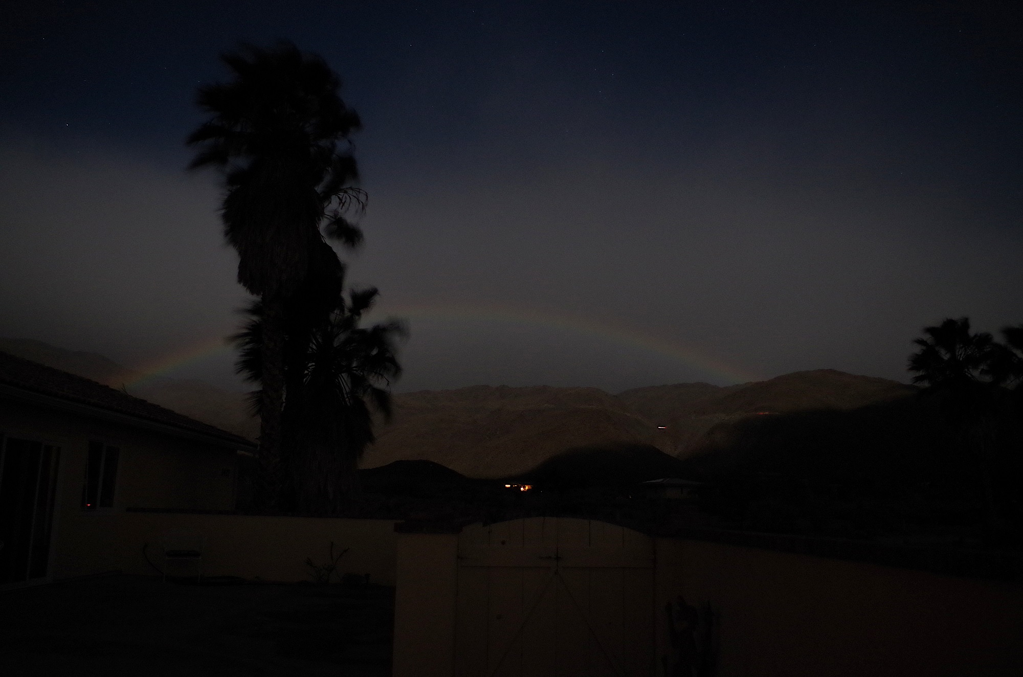 A lunar rainbow or moonbow stretching over the mountains at night in Anza-Borrego Desert State Park
