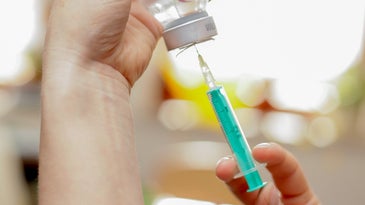 a person putting a vaccine into a syringe.