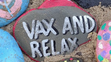 A beach rock painted with the phrase vax and relax for the COVID-19 pandemic