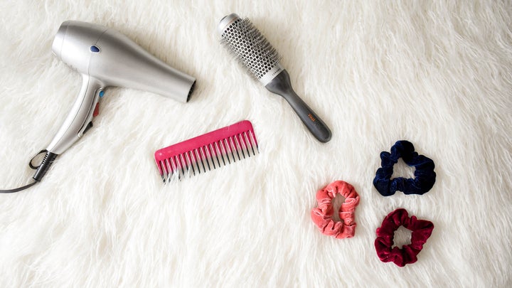 hair dryer, comb, brush, and scrunchies on a furry white rug