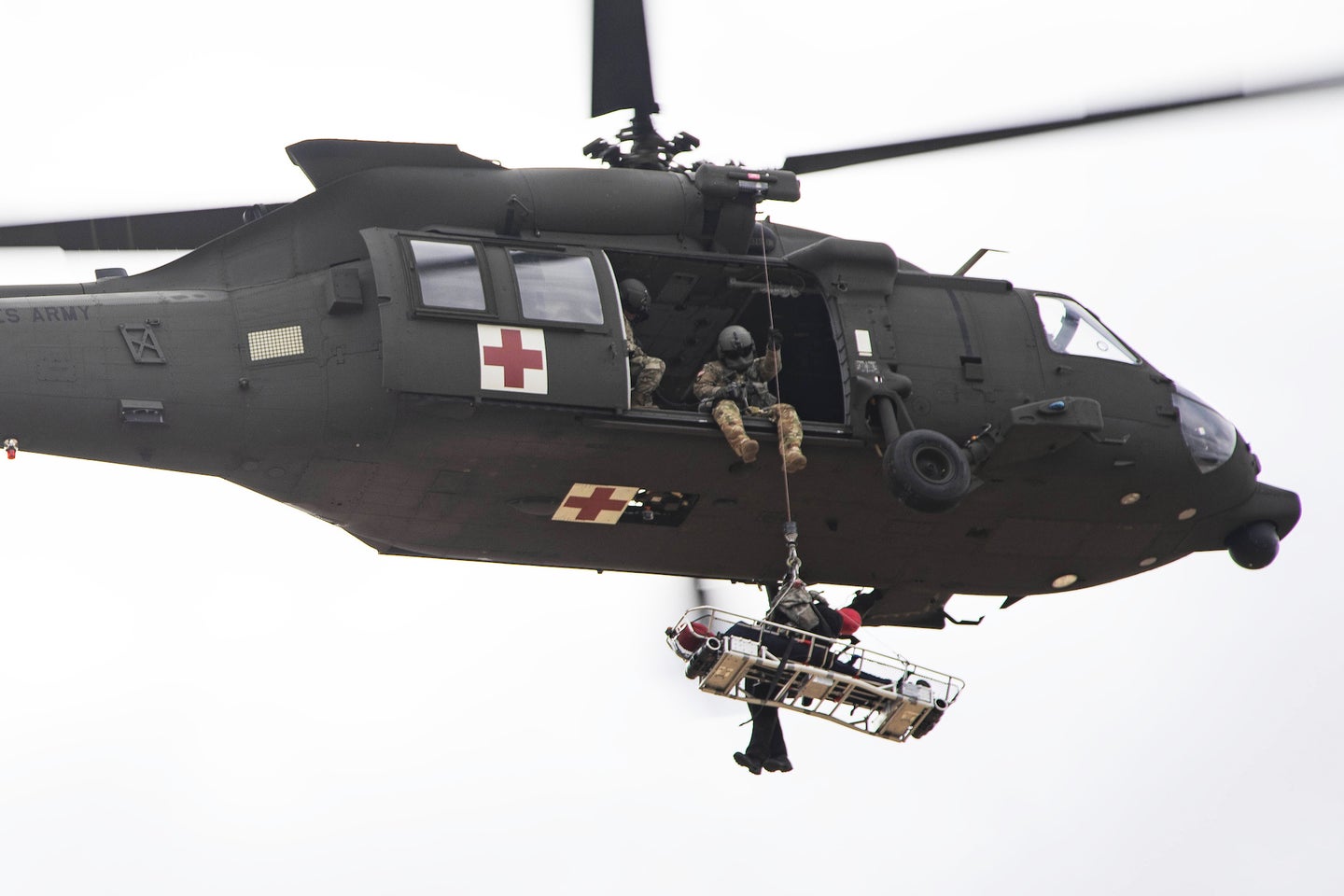 A Black Hawk helicopter with a rescue basket beneath it.