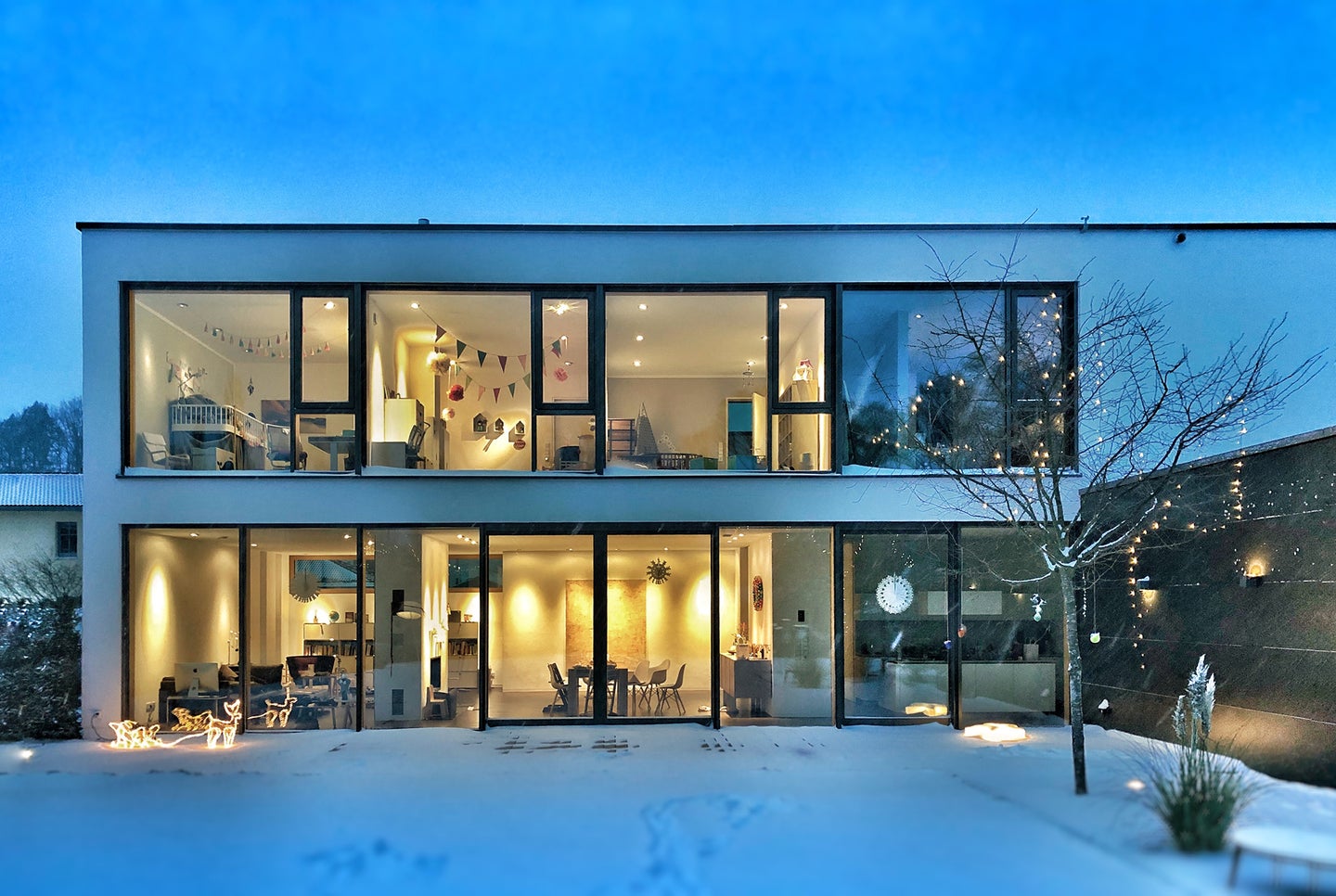 modern house with two floors, the best home security system cameras, and lights on inside