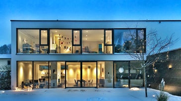 modern house with two floors, the best home security system cameras, and lights on inside