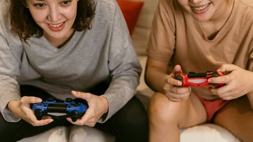 Two friends playing video games on the couch.