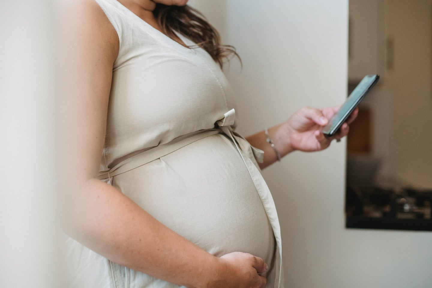 Pregnant woman checking phone notifications.