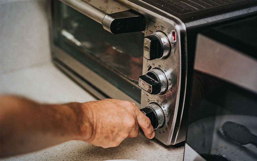 person turning the dial on the best toaster oven