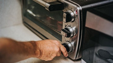 person turning the dial on the best toaster oven